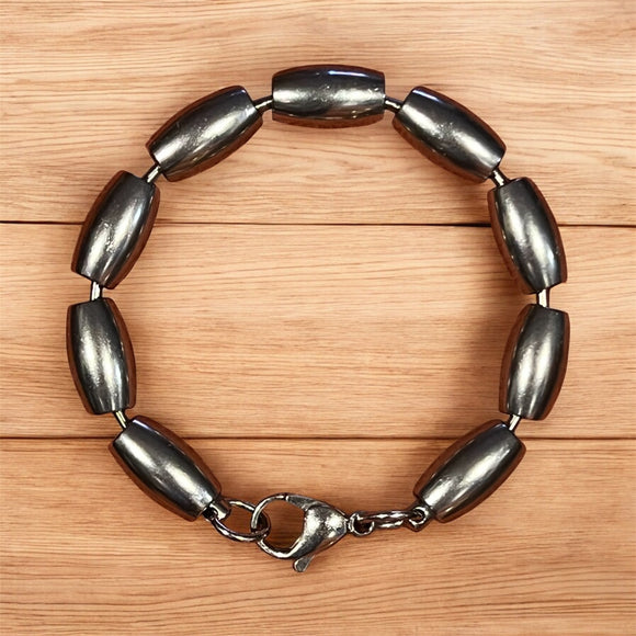 Silver bracelet with oval beads on a wooden surface