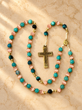 Full aquamarine and pink cat’s-eye rosary with the crucifix fully visible on a softly lit ivory devotional background