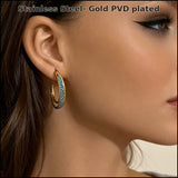 Yana blue accent hoop earrings in stainless steel with gold PVD plating shown on model