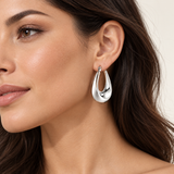 Silver stainless steel elongated hoop earring worn by a model